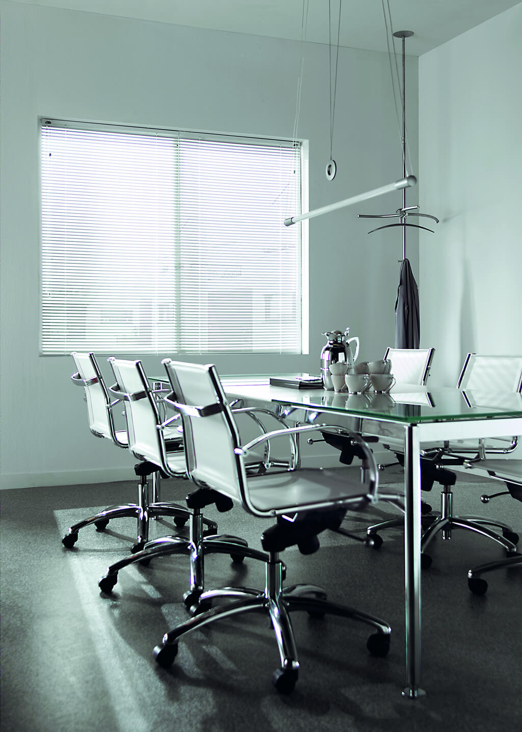 Weiße Alu-Jalousie in einem schlichten Konferenzraum mit Glastisch und weißen Stühlen