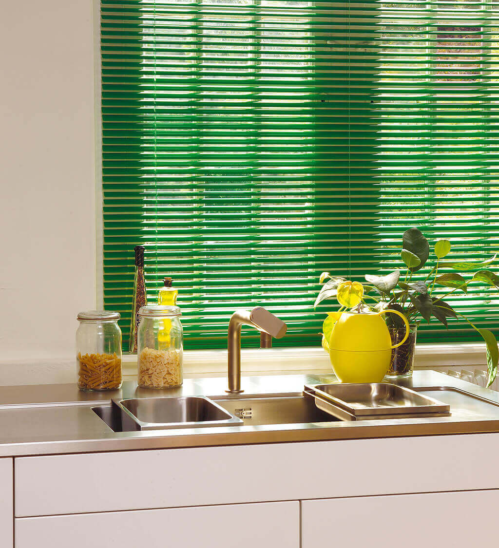 Grüne Alu-Jalousie mit schmalen Lamellen am Küchenfenster