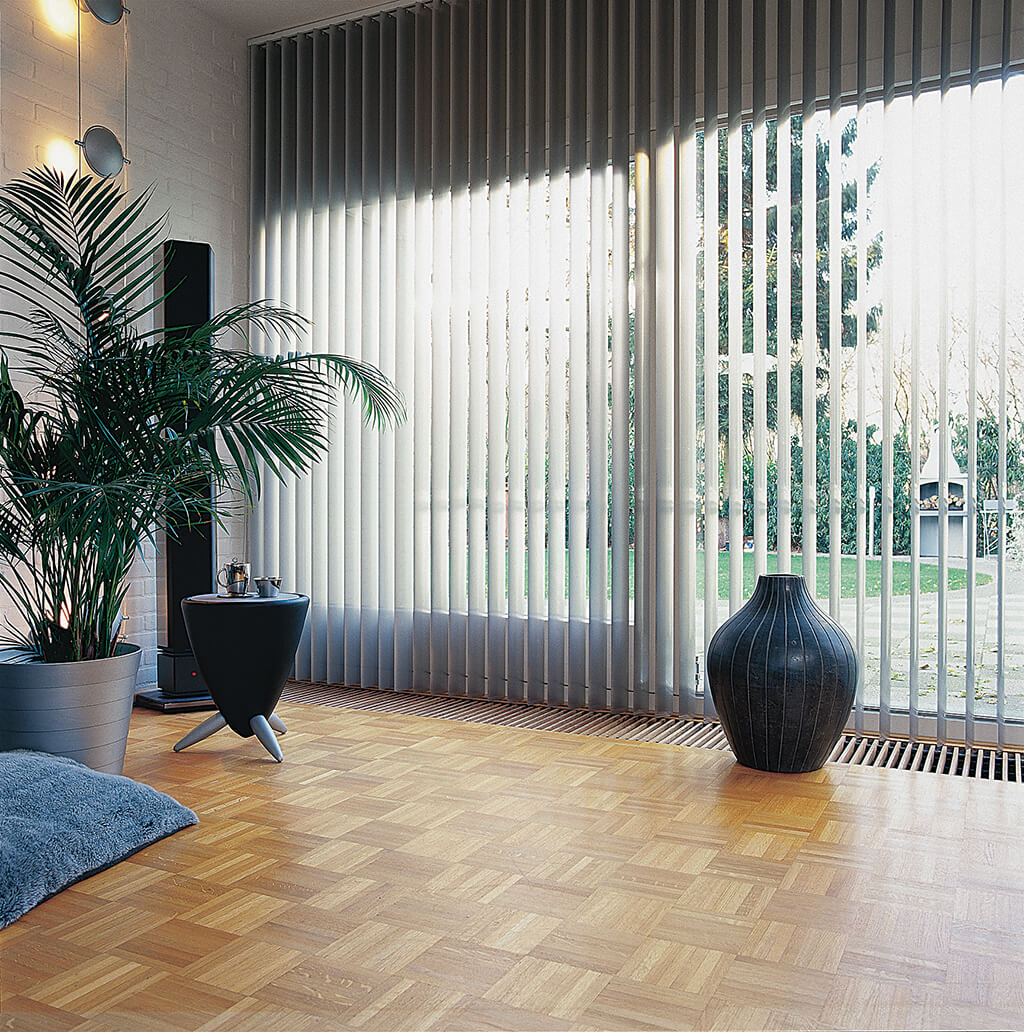 Weißer Lamellenvorhang am Wohnzimmerfenster mit Blick in den Garten