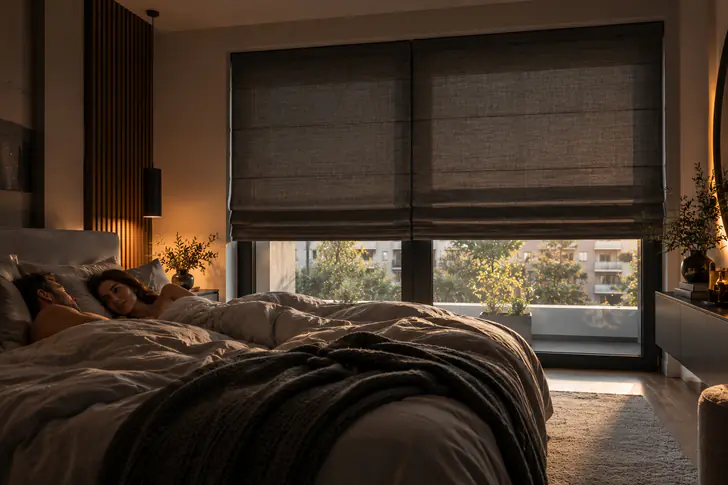 Dunkelgraue Raffrollos im Schlafzimmer am Morgen