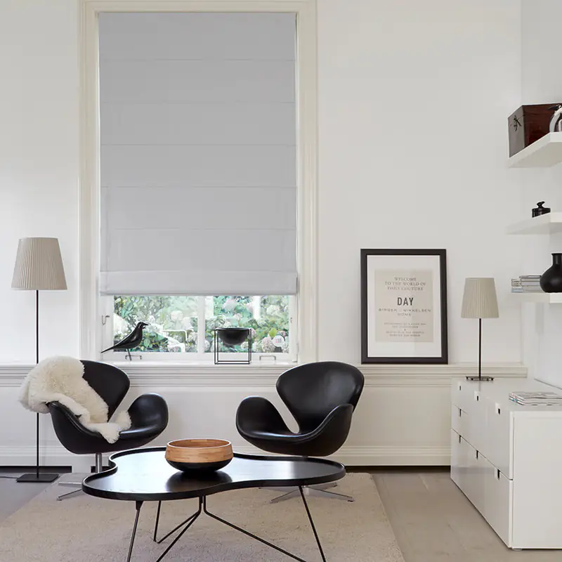 Hellgraues Raffrollo im Wohnzimmer mit schwarzen Designer-Sesseln